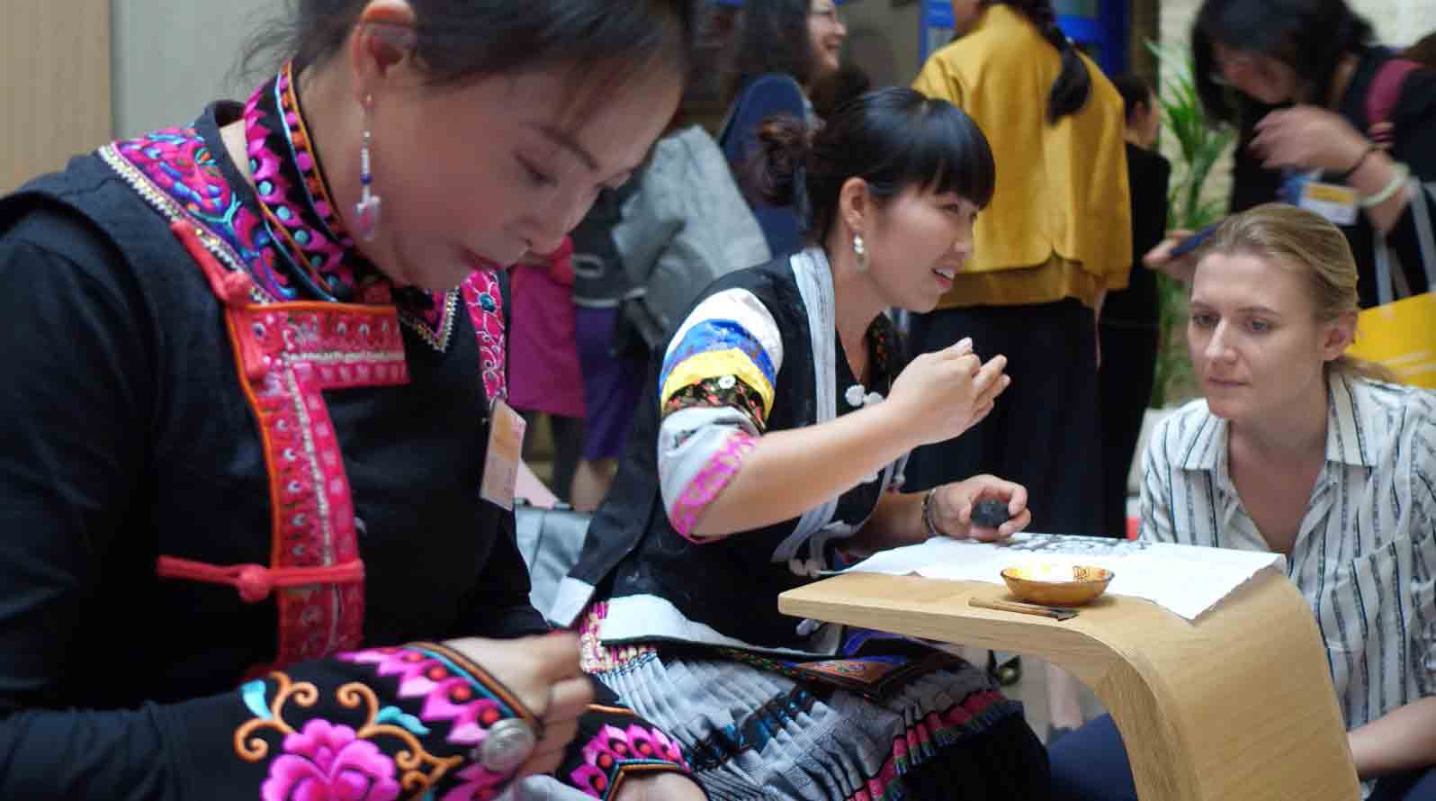 2018年6月，英国伦敦“2018年女性可持续发展国际论坛暨女性手工艺创新展”活动期间，来自彝族和苗族的绣娘向现场中外来宾展示精湛的传统非遗手工技艺.jpg